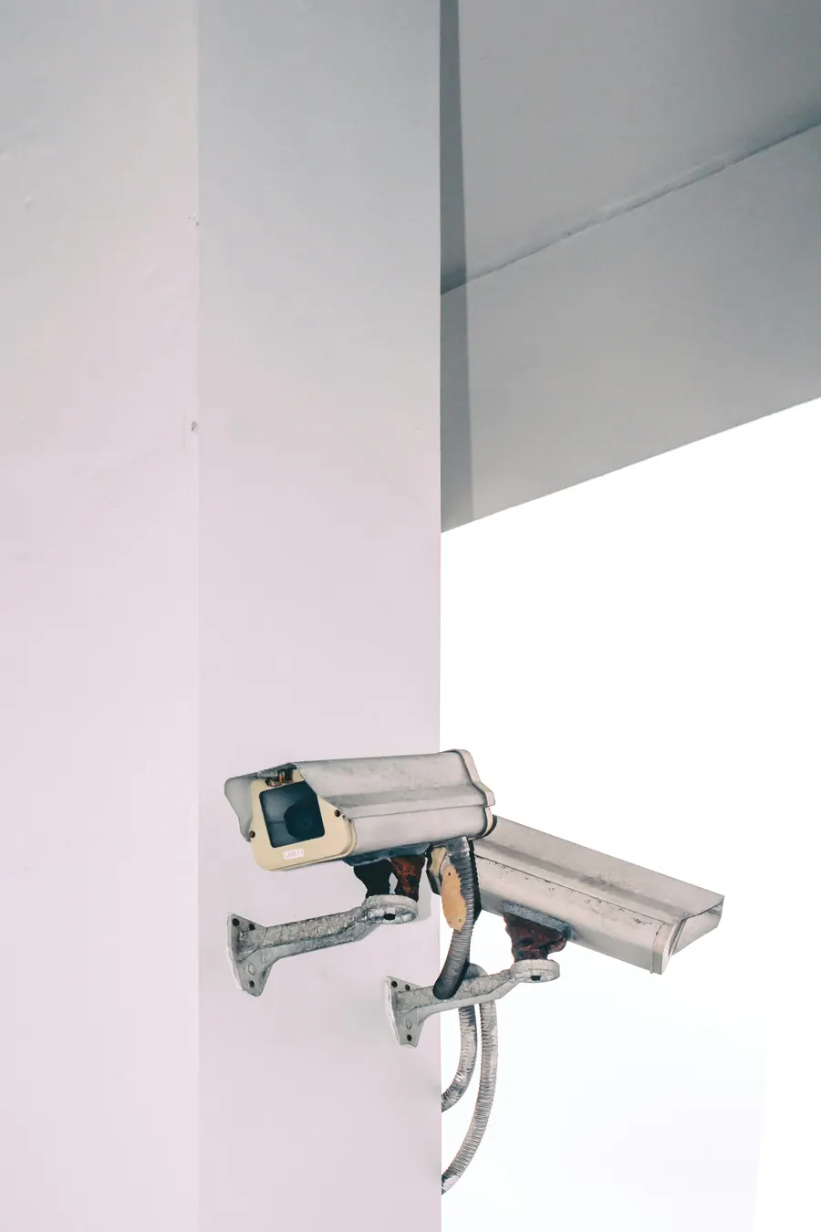 Two weatherproof bullet cameras on brackets fixed to a white pillar